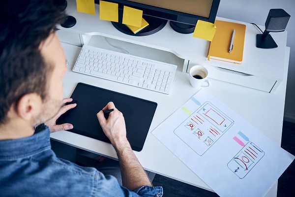 A Web Designer Preparing Website Outlook In His Digital Tablet At His Workplace. 