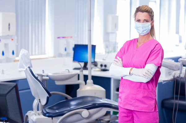Leading Woman Dentist Wearing Surgical Mask - Standing And Staring Towards The Camera 